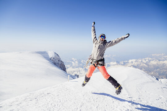 Mountaineer celebrates summit achievement in bright winter landscape