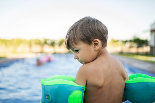 Little boy standing by the pool with floaties, about to jump in