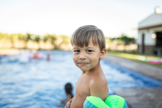 Little boy standing by the pool with floaties, about to jump in