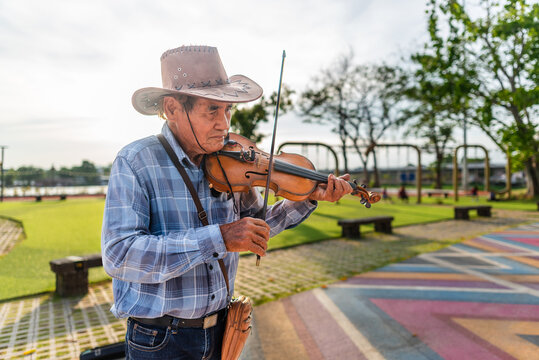 Violinist busking in public park in Thailand at sunset