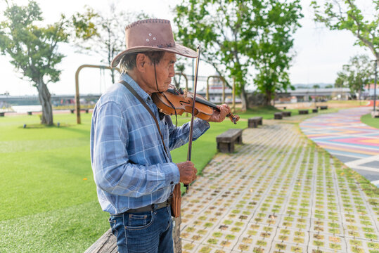Violinist busking in public park in Thailand at sunset
