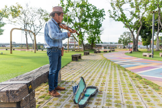 Violinist busking in public park in Thailand at sunset