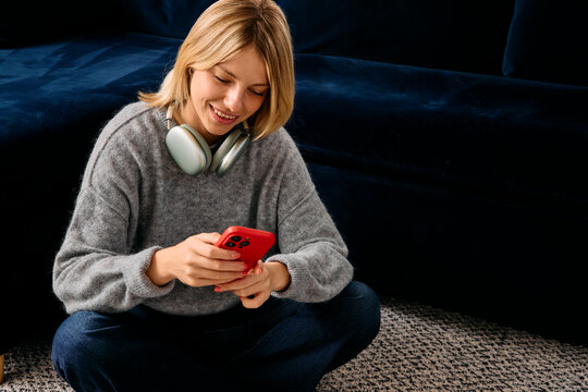 Woman wearing headphones using her phone at home