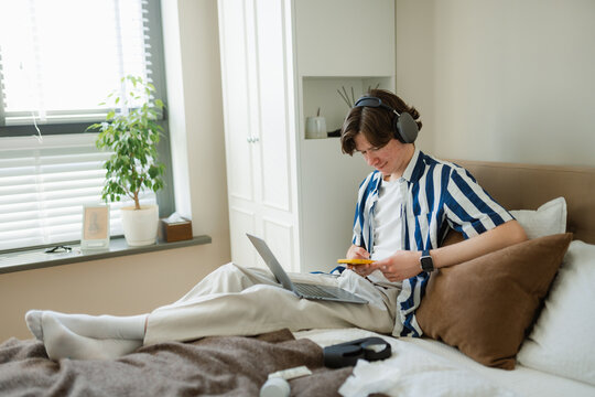 The man uses a mobile phone and laptop at home