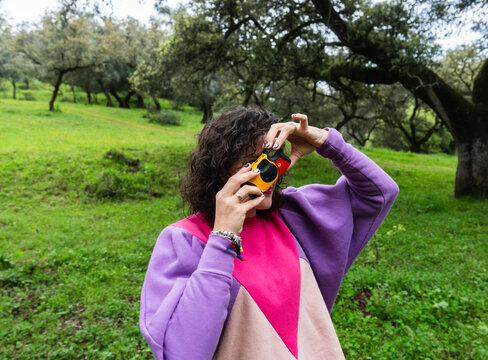 Woman taking pictures with disposable camera in oak forest