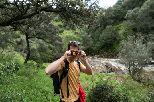 Hiker taking pictures with disposable camera in nature