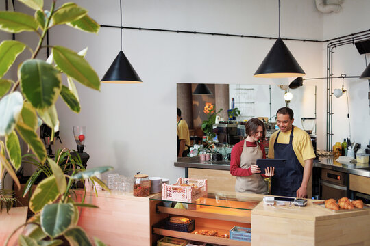 Small Business Owners Working With Tablet in Cozy Cafe