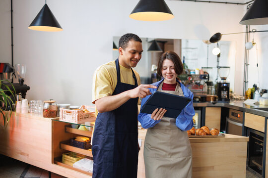 Small Business Baristas Using Tablet Together in coffee shop bakery