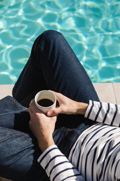 A man drinking coffee by the pool