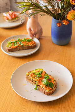 Anonymous hand reaching for colorful avocado toast on plate