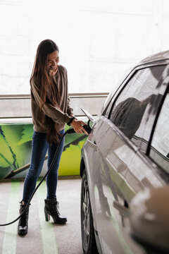 Woman Charging Electric Car in an Eco-Friendly Urban Garage