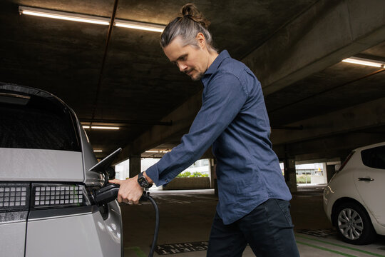 Man Charging Electric Vehicle in Underground Car Park