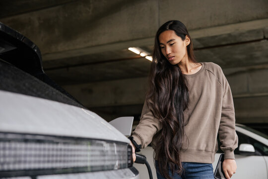 Woman Charging Electric Car in Indoor Parking Garage