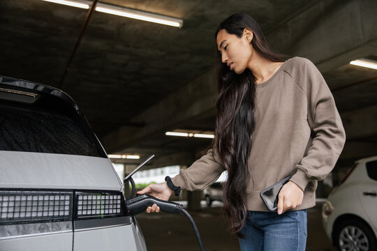Woman Charging Electric Car in Underground Parking Lot