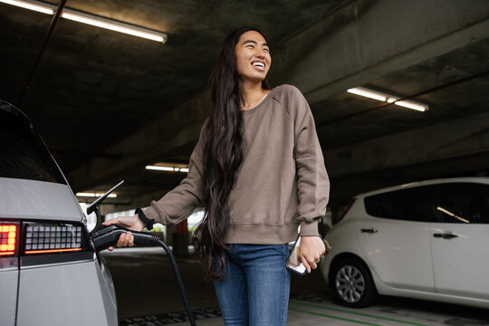 Person Charging Electric Vehicle in Parking Garage