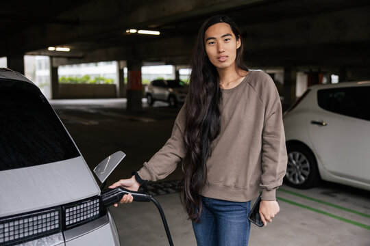 Person Charging Electric Car in Urban Parking Garage Setting