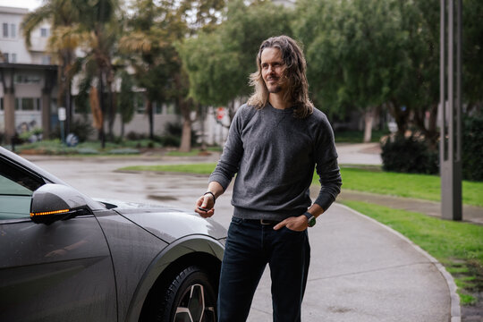 Casual Individual Standing by a Parked Car on a Rainy Day