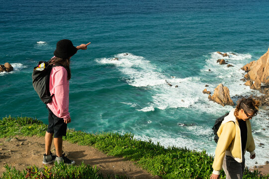 A queer couple walking down to rocky beach
