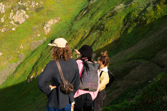 Three friends looking down to a mountain hiking path