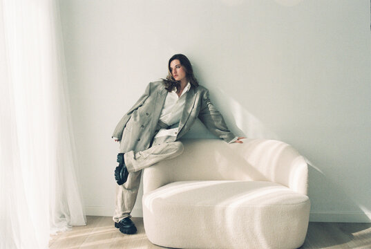 Film photography of young woman posing on modern sofa