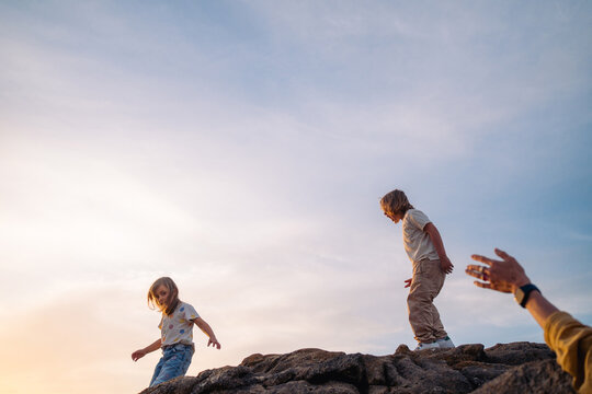 Children standing on rocks under evening sky