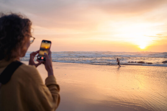 Capturing sunset with phone on shoreline