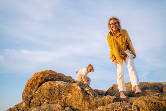 Helping child climb rocks at beach