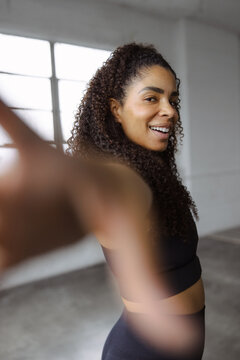 Confident Woman in Fitness Attire Reaching Forward with a Smile