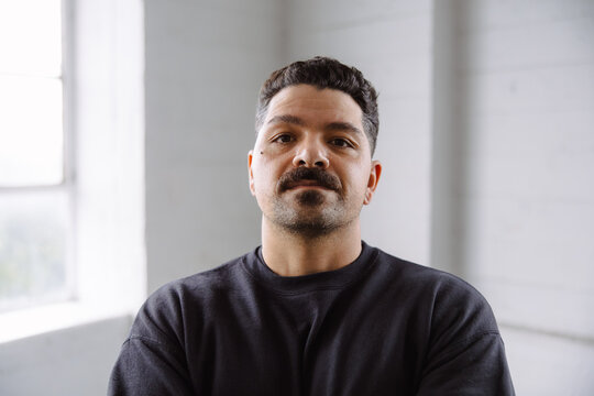 Confident Man Posing Indoors with Natural Lighting and Casual Style
