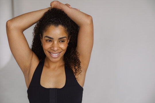 Confident Woman in Activewear Smiling with Hands Overhead