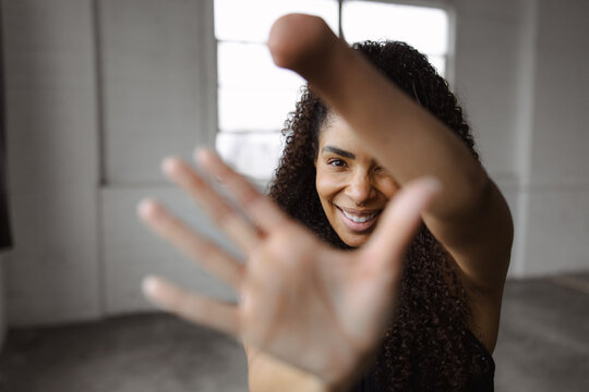Confident Woman Smiling and Reaching Towards Camera in a Sunlit Room