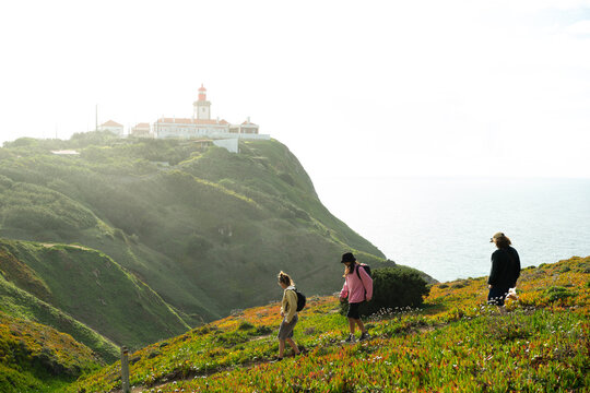 Three people walking down hiking trail by lighthouse