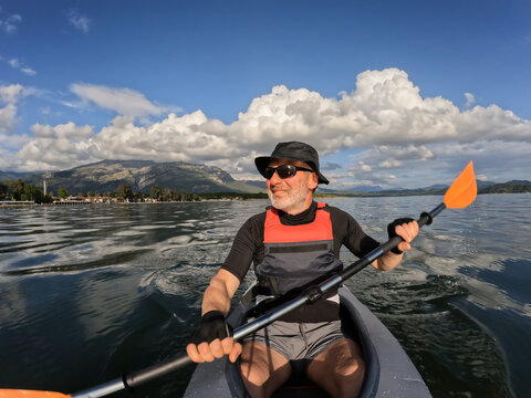 Senior man rowing his canoe on a lake. His face content and relaxed