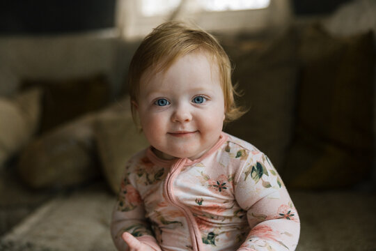 Adorable Baby Sitting Indoors Wearing a Floral Pattern Outfit