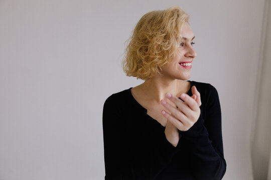 Smiling Woman Clapping Hands in a Bright Minimalist Setting