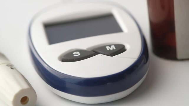 Close up motion footage of diabetes testing equipment including glucometer and medication bottle
