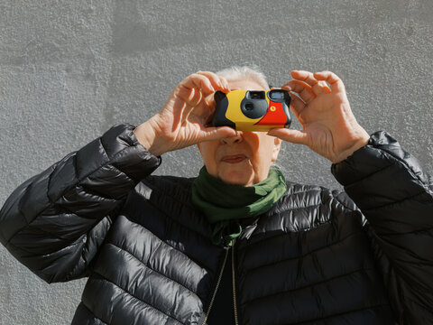 Elderly person capturing a moment with a camera in an urban outdoor 