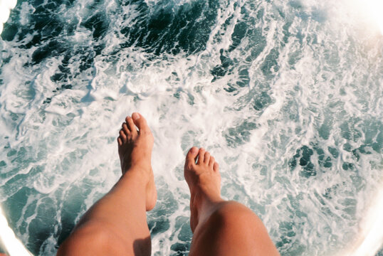 Feet Dangling Above Ocean Waves
