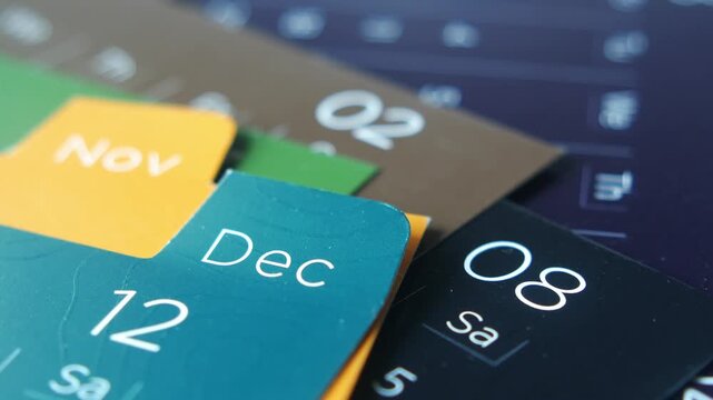 Cinematic macro shot of monthly calendar tabs showing november and december with focus shifting across dates