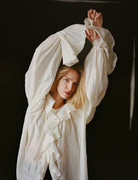 Model Poses Gracefully in Oversized White Ruffled Shirt Indoors
