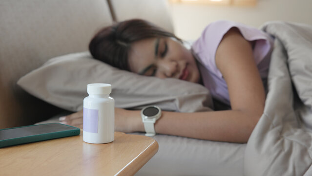 Young adult woman black asia people take herbal CBD pill bottle lying down on soft cozy bed deep sleep aid calm. Waking up happy serene relax drug anti aging good health care fall asleep till morning.