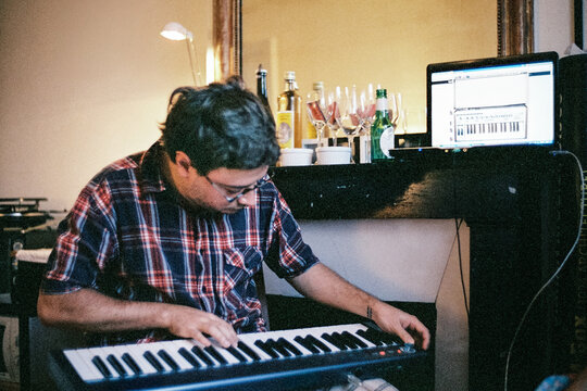 Man Playing Keyboard in Cozy Home Studio
