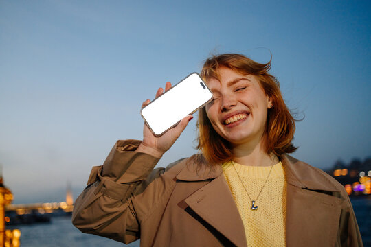 A woman holds a mobile phone with white screen