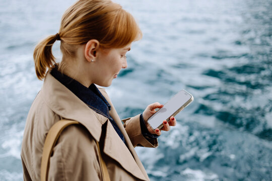 A woman uses a mobile phone against the background of the sea