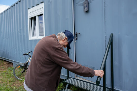 Senior man entering converted shipping container home
