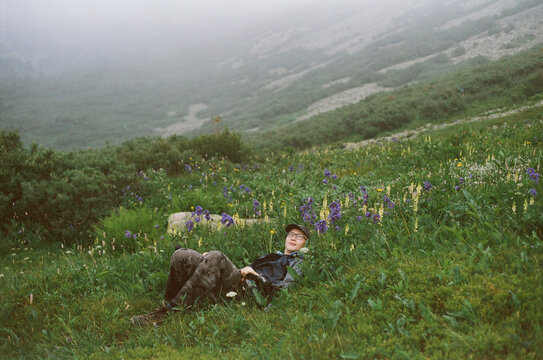 Young person relaxing in a lush green field with wildflowers 