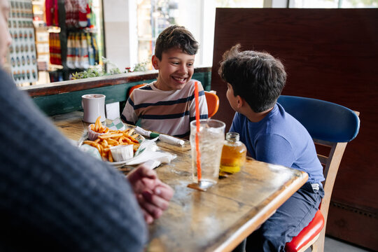 Two Boys Sharing Laughter Over Food at a Cozy Restaurant Table