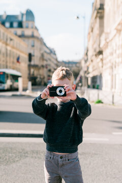 A young boy takes pictures while exploring the streets of Paris