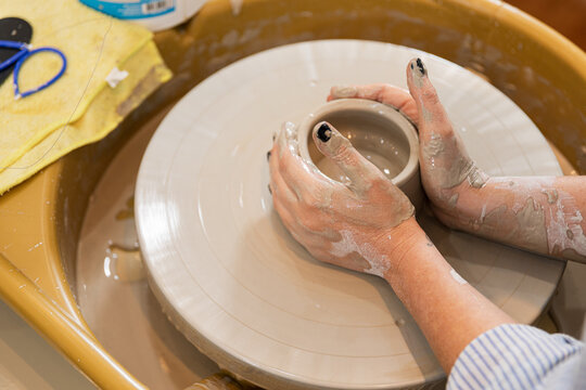 Hands shaping pottery in a focused environment