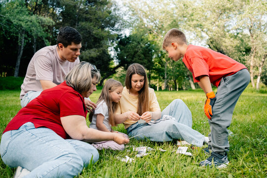 Group sorting stickers on grass in forest clearing
